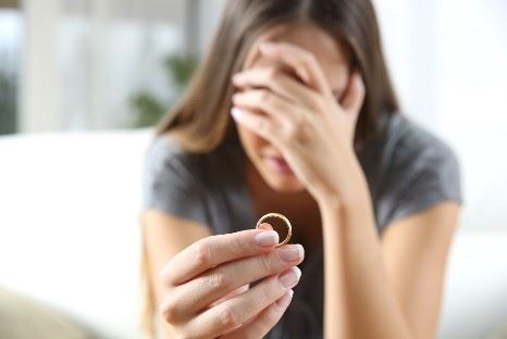 crying woman looking at wedding ring